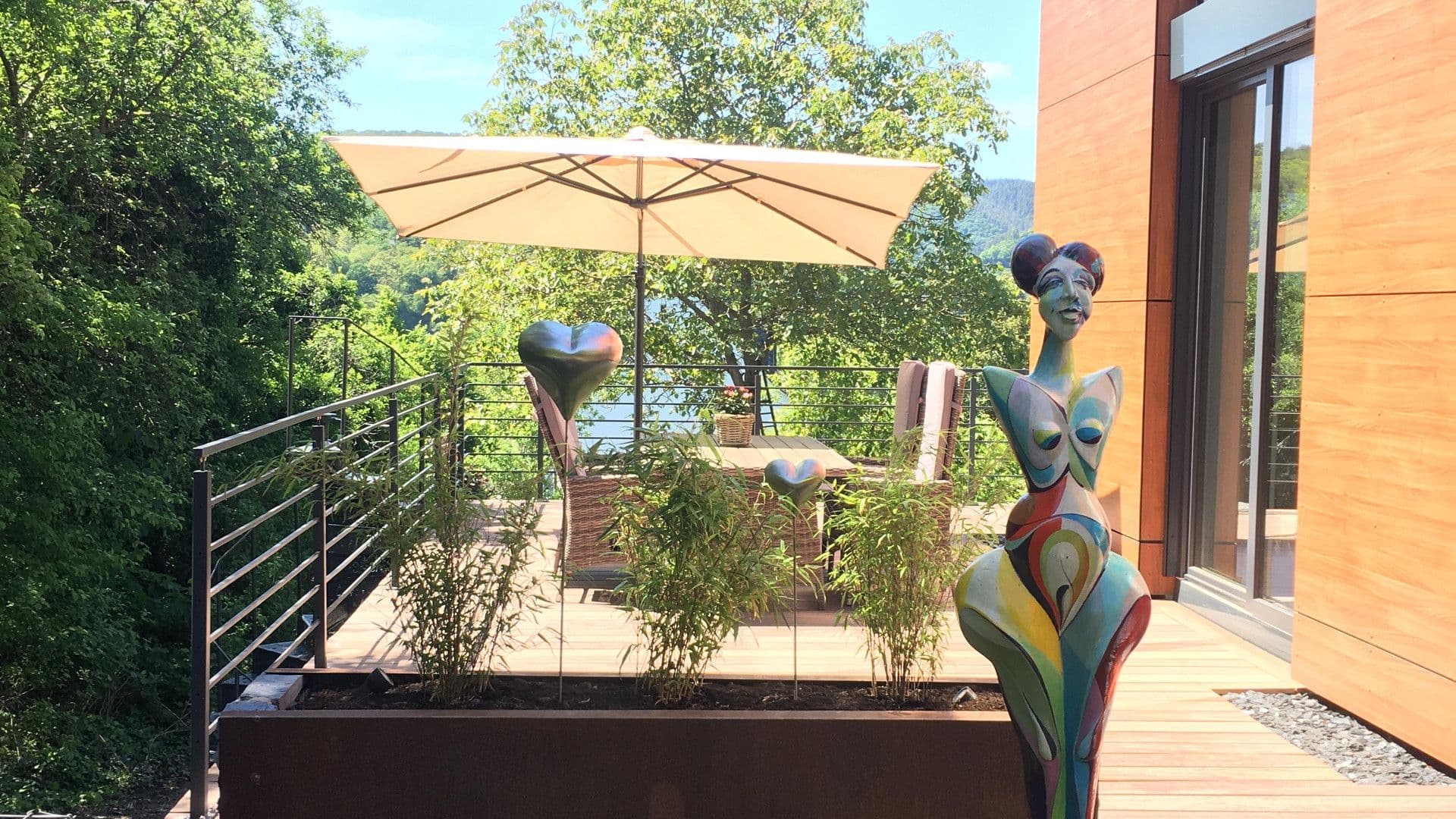 Terrasse mit Kunstskulpturen und Sonnenschirm