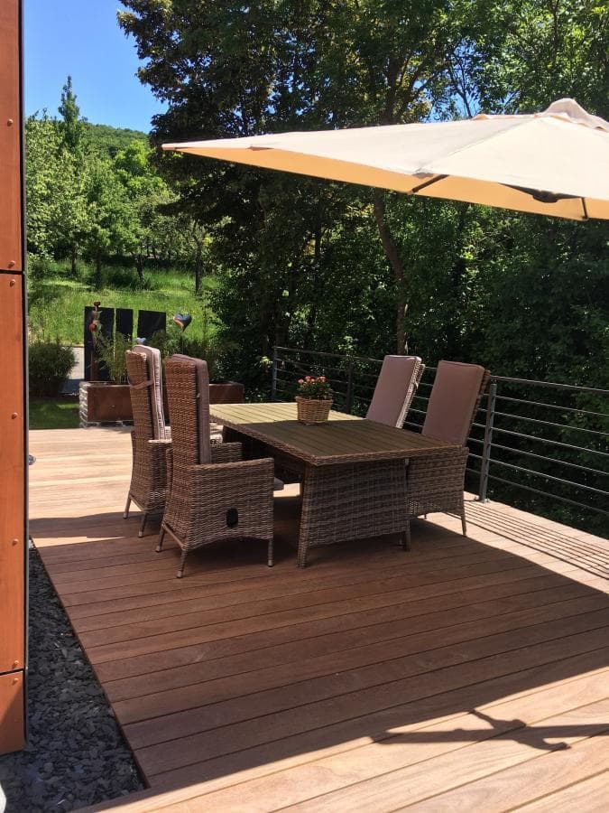Holzterrasse mit Rattanmöbeln und Sonnenschirm